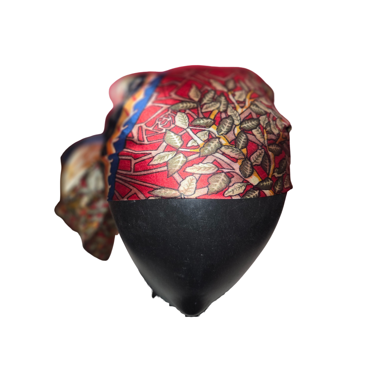 Colorful headscarf with leaf pattern on a black mannequin head against a white background